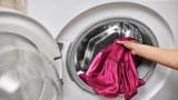Eine Seidenbluse wird in eine Waschmaschine gesteckt.