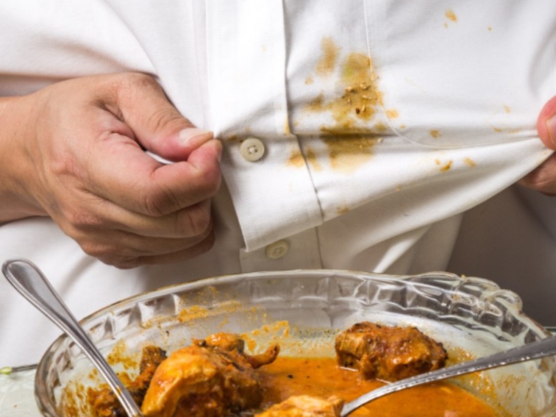 Konzeptbild: Curryfleck entfernen. Ein gelber Curryfleck auf dem Hemd eines Mannes.