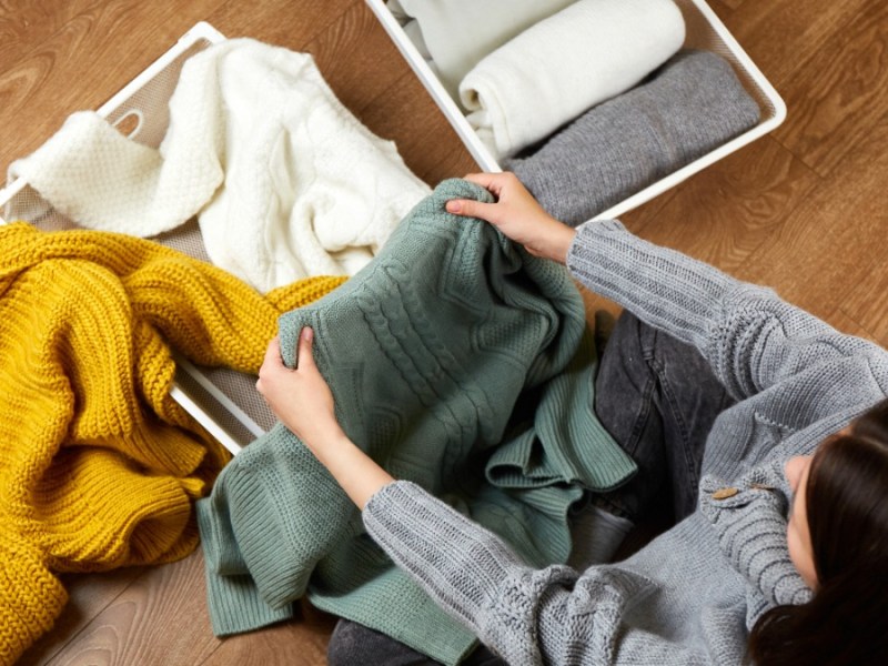 eine Frau sitzt auf dem Boden und faltet ihre Pullover