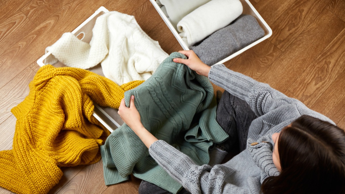 eine Frau sitzt auf dem Boden und faltet ihre Pullover