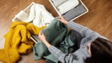 eine Frau sitzt auf dem Boden und faltet ihre Pullover