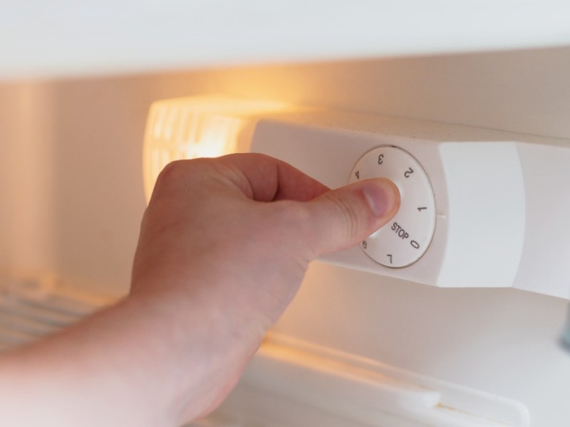 jemand verstellt die Temperatur in einem Kühlschrank