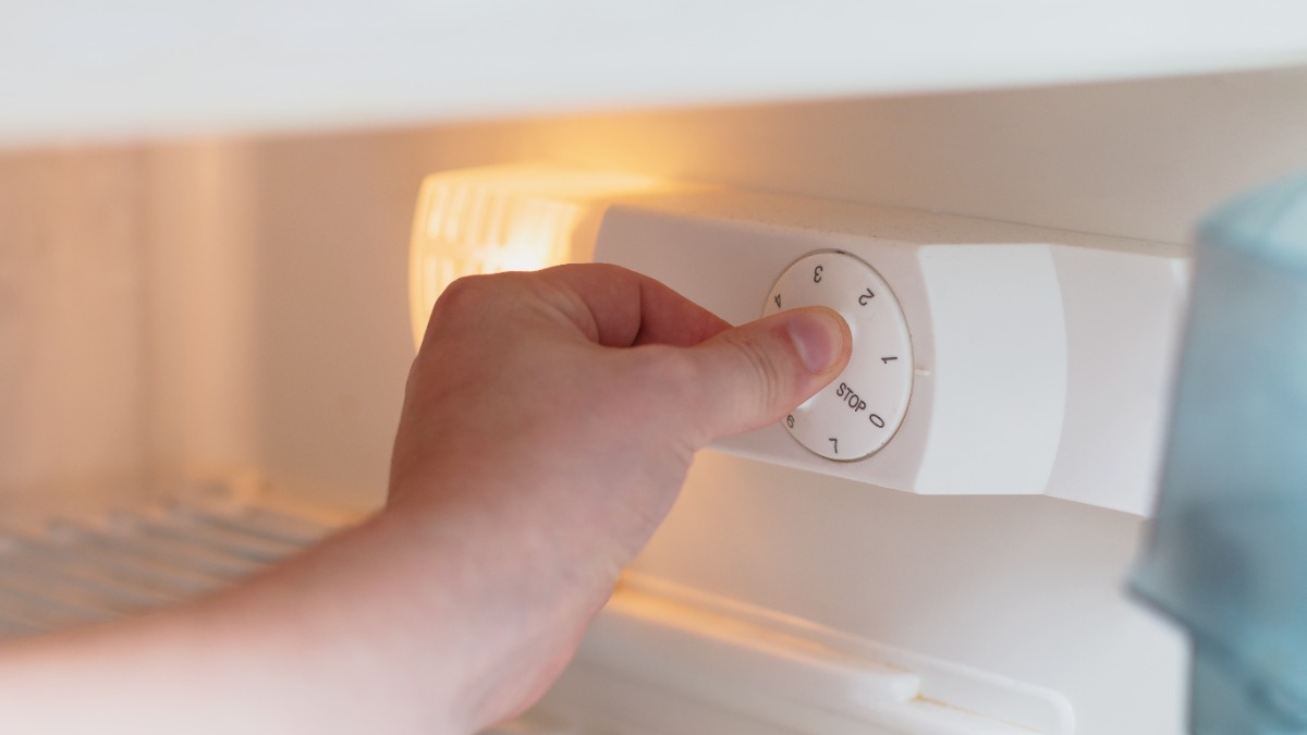 jemand verstellt die Temperatur in einem Kühlschrank