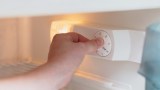 jemand verstellt die Temperatur in einem Kühlschrank
