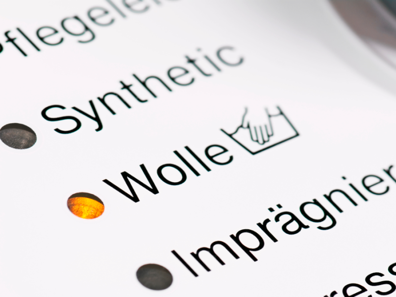 Auf einer Waschmaschine sieht man verschiedene Programme, unter anderem das für Wolle.