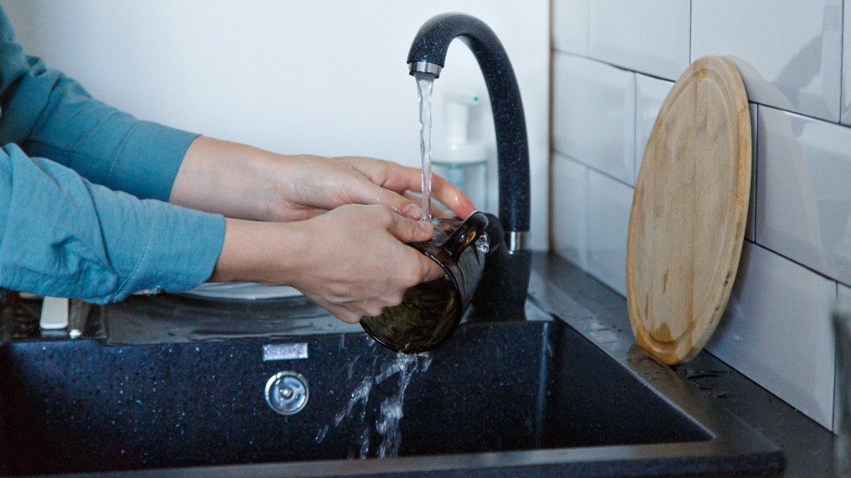 eine Tasse wird über einer schwarzen Spüle abgewaschen