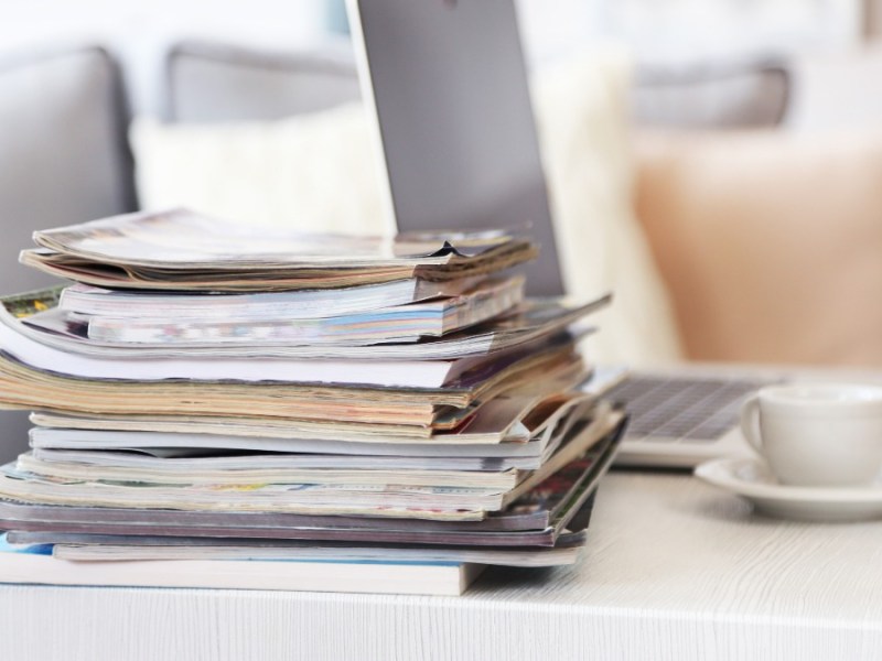 Magazine liegen gestapelt auf dem Tisch neben einem Laptop