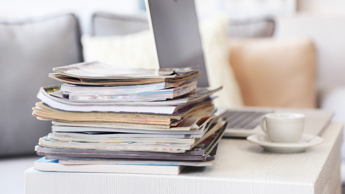 Magazine liegen gestapelt auf dem Tisch neben einem Laptop