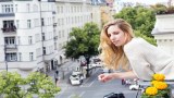 Eine Frau lehnt sich von einem Balkon.