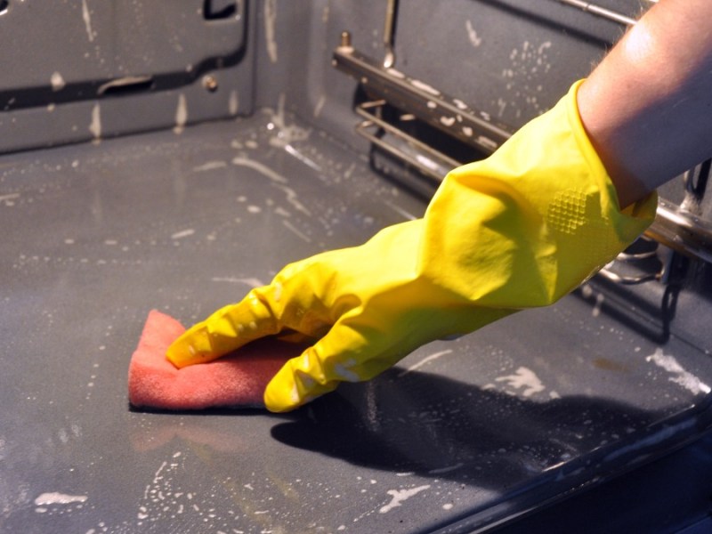 Backofen reinigen mit einem Handschuh und Lappen