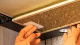 Fettige Dunstabzugshaube wird zum Reinigen ausgebaut.