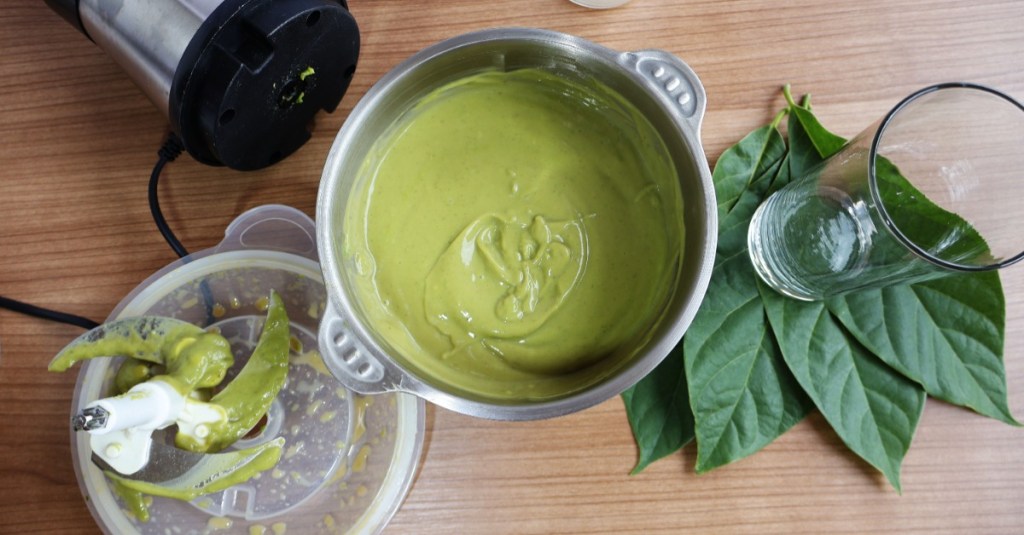 Mixer reinigen: ein Topf mit einer grünen Sauce steht neben einem dreckigen Mixer