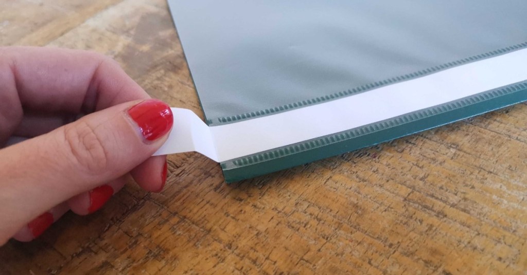 eine Hand schiebt den Papierstreifen zurück in den Schnellhefter