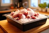 Eine Plastikschale mit Hähnchenfleisch und Eis