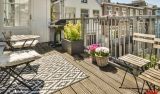 Ein Outdoorteppich auf einem Balkon mit Holzmöbeln und Pflanzen.