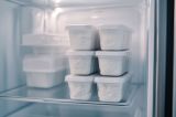 Einige Plastikgebhälter mit Quark im Tiefkühlfach.