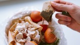 ein Teebeutel wird über einen Mülleimer gehalten