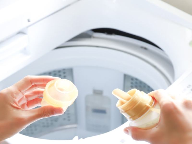 Ein Weichspüler wird in eine Waschmaschine geschüttet.