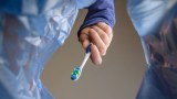 eine Zahnbürste wird in eine Mülltüte geworfen