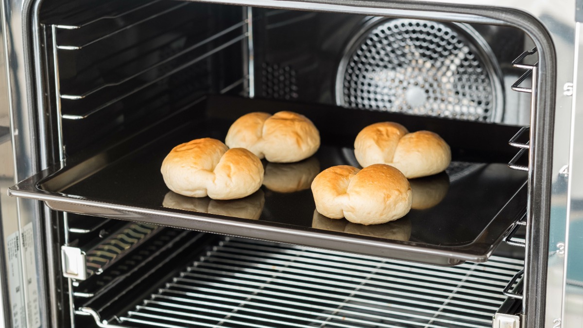 vier Brötchen auf einem Backblech im Ofen