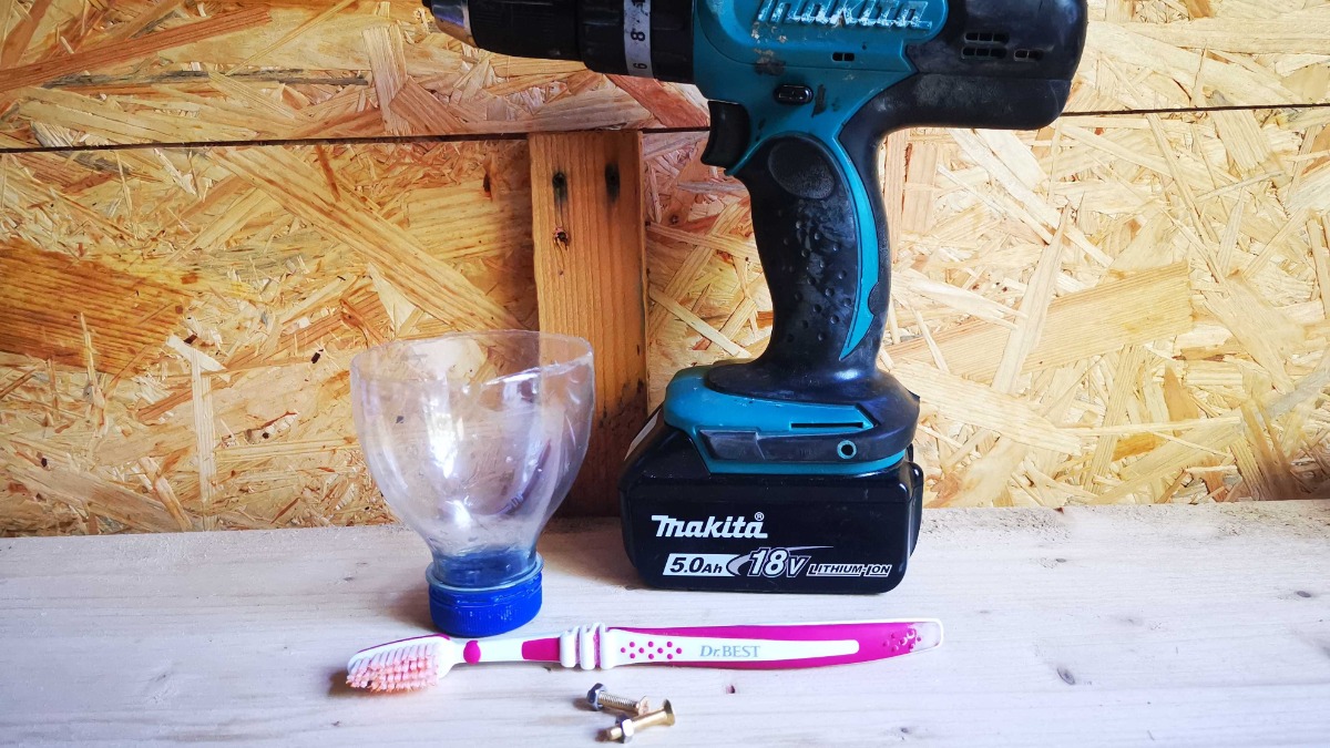 ein Akkuschrauber, eine Zahnbürste, zwei Schrauben und eine abgeschnittene Plastikflasche