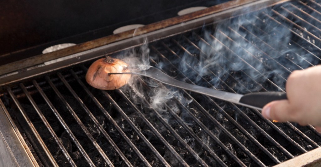 ein Grillrost wird mit einer Zwiebel abgerieben