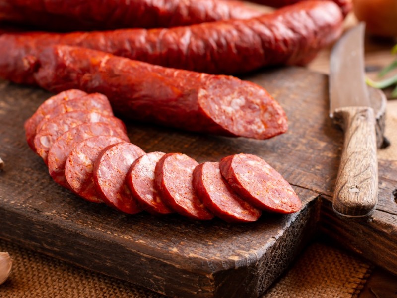 Salami, in Scheiben geschnitten, liegt auf einem Küchenbrett.