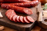 Salami, in Scheiben geschnitten, liegt auf einem Küchenbrett.