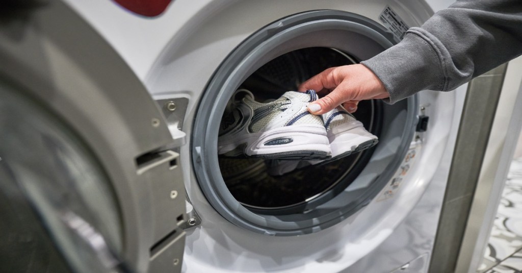 Turnschuhe werden in eine Waschmaschine gesteckt.
