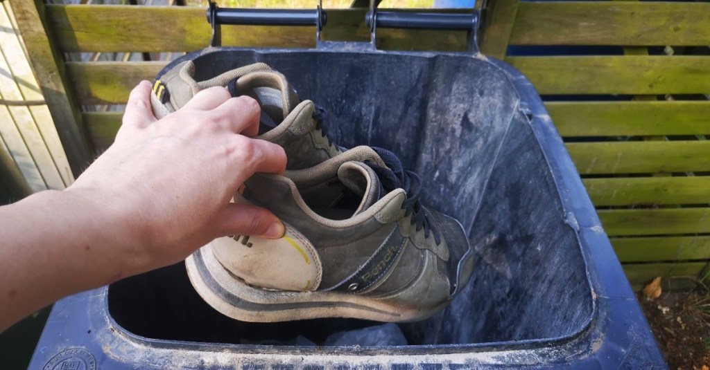 alte Schuhe werden in einer Restmülltonne entsorgt