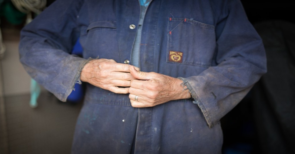 Eine Person mit blauer Arbeitskleidung.