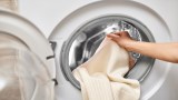 Ein Kaschmirpullover wird in eine Waschmaschine gesteckt.