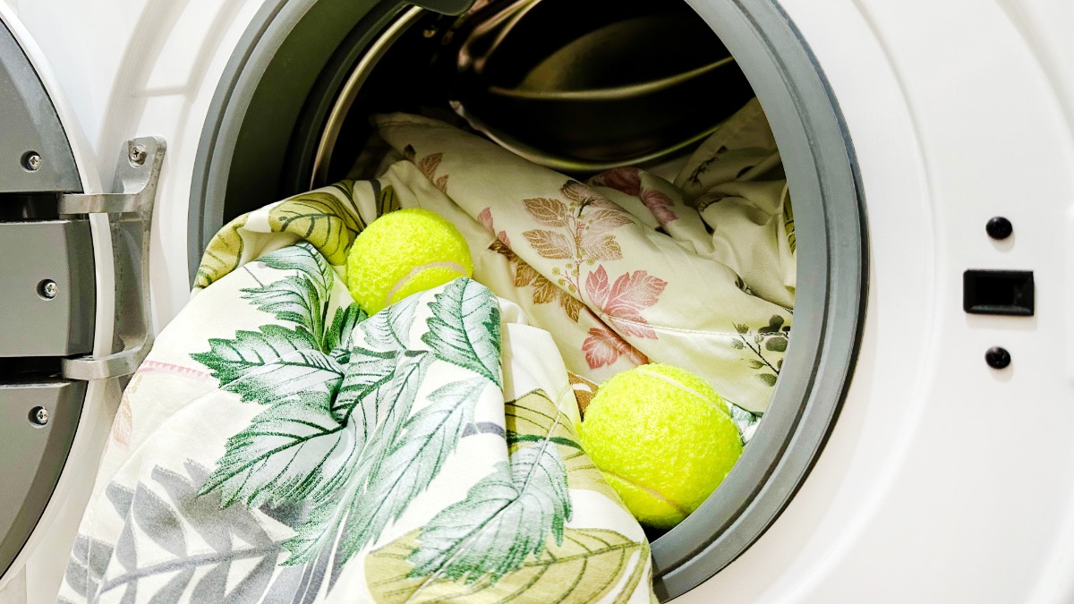 Tennisbälle und Bettwäsche liegen in einer Waschmaschine