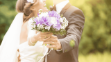 wie viel geld zur hochzeit schenken, Brautpaar hält Brautstrauß in die Kamera