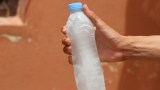 eine Hand hält eine Plastikflasche mit gefrorenem Wasser