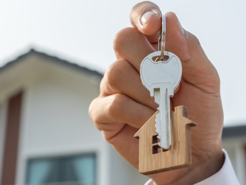 Ein Immobilienmakler, der einen Haustürschlüssel in der Hand hält.