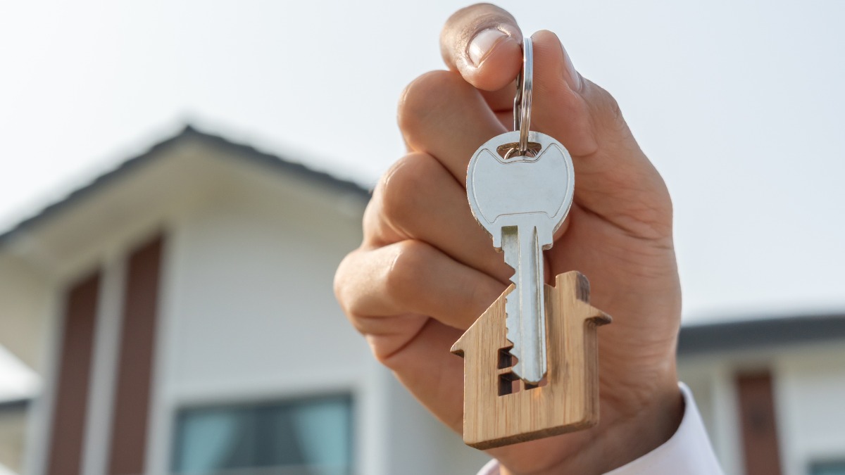 Ein Immobilienmakler, der einen Haustürschlüssel in der Hand hält.