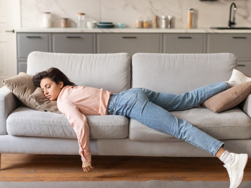 Eine Frau, die erschöpft auf einer Couch liegt.