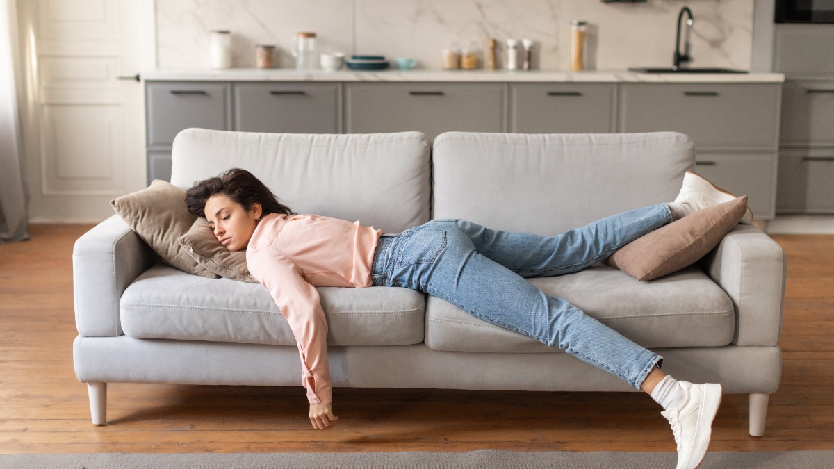 Eine Frau, die erschöpft auf einer Couch liegt.