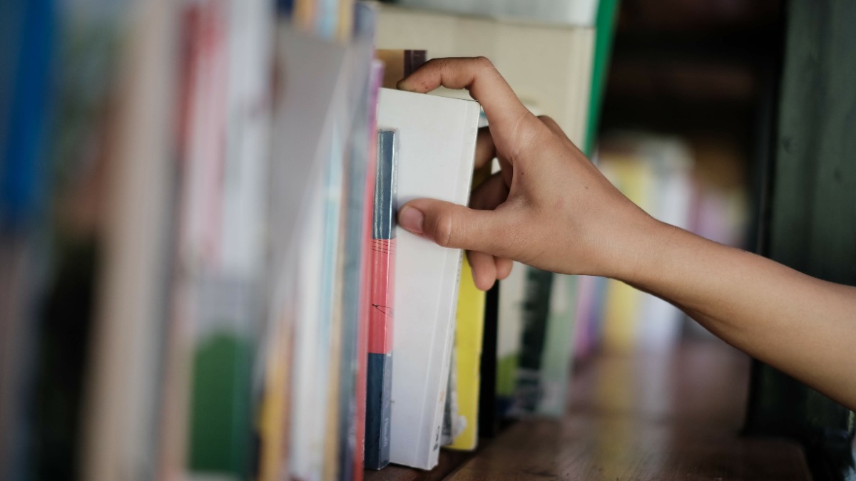 jemand nimmt ein Buch aus einem Bücherregal