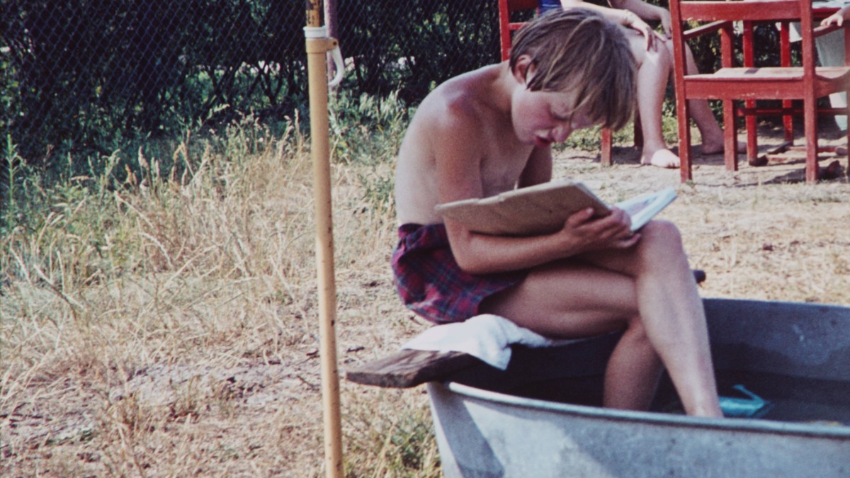 Aufnahme eines Jungen im Jahr 1960, der ein Buch liest, während er auf dem Rand einer Zinnwanne sitzt
