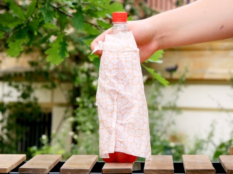 Eine Limonadenflasche wird mit einem feuchten Tuch umwickelt.