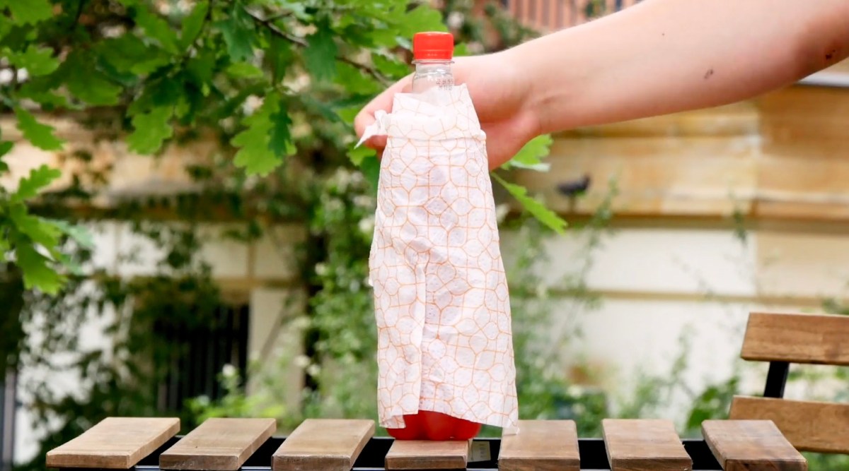 Eine Limonadenflasche wird mit einem feuchten Tuch umwickelt.