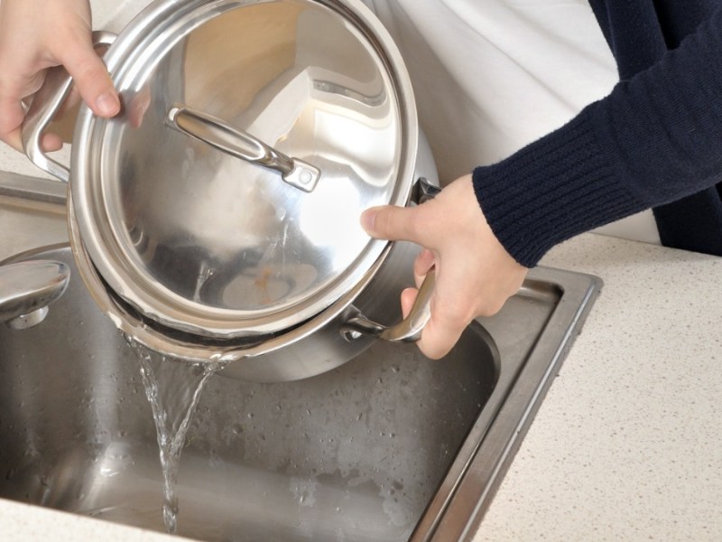 jemand gießt heißes Wasser in den Abfluss