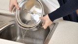 jemand gießt heißes Wasser in den Abfluss