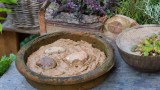 Eine Schüssel mit Lehm in einem Garten. Mit dieser Nisthilfe unterstützt du Insekten, Bienen und Vögel.