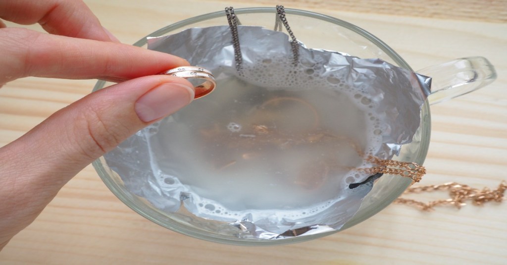 Ein Ring wird in eine Mischung aus Natron und Wasser gesteckt.