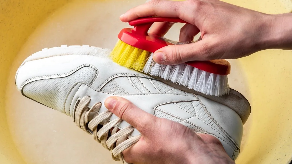 Weiße Sneaker mit einer Bürste reinigen.