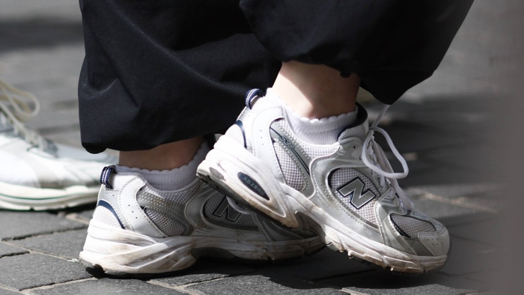 jemand trägt weiße Turnschuhe zu einer schwarzen Hose