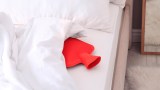 Rote Wärmflasche in einem Bett.